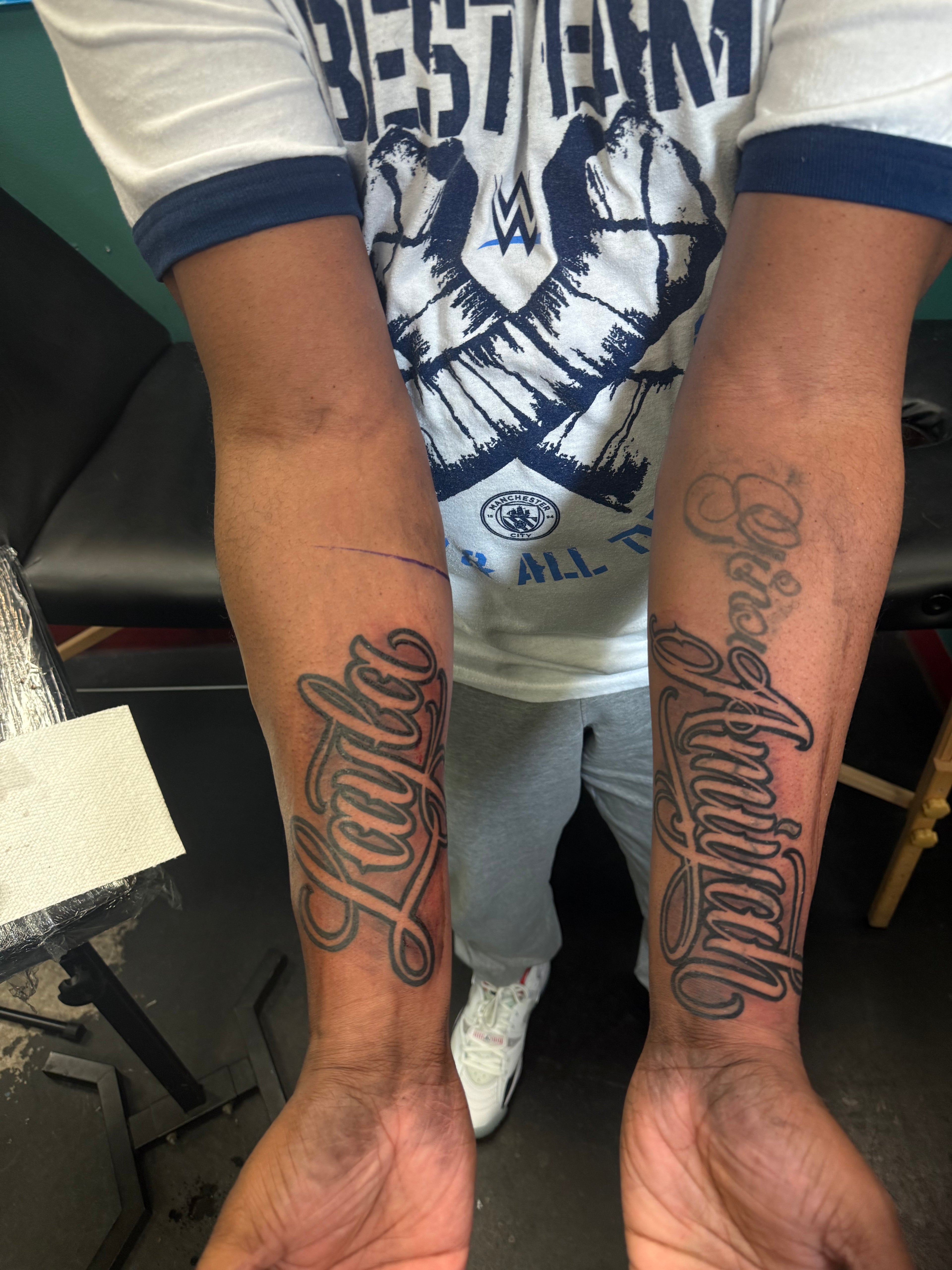 Two arms with tattoos on a blurred indoor background