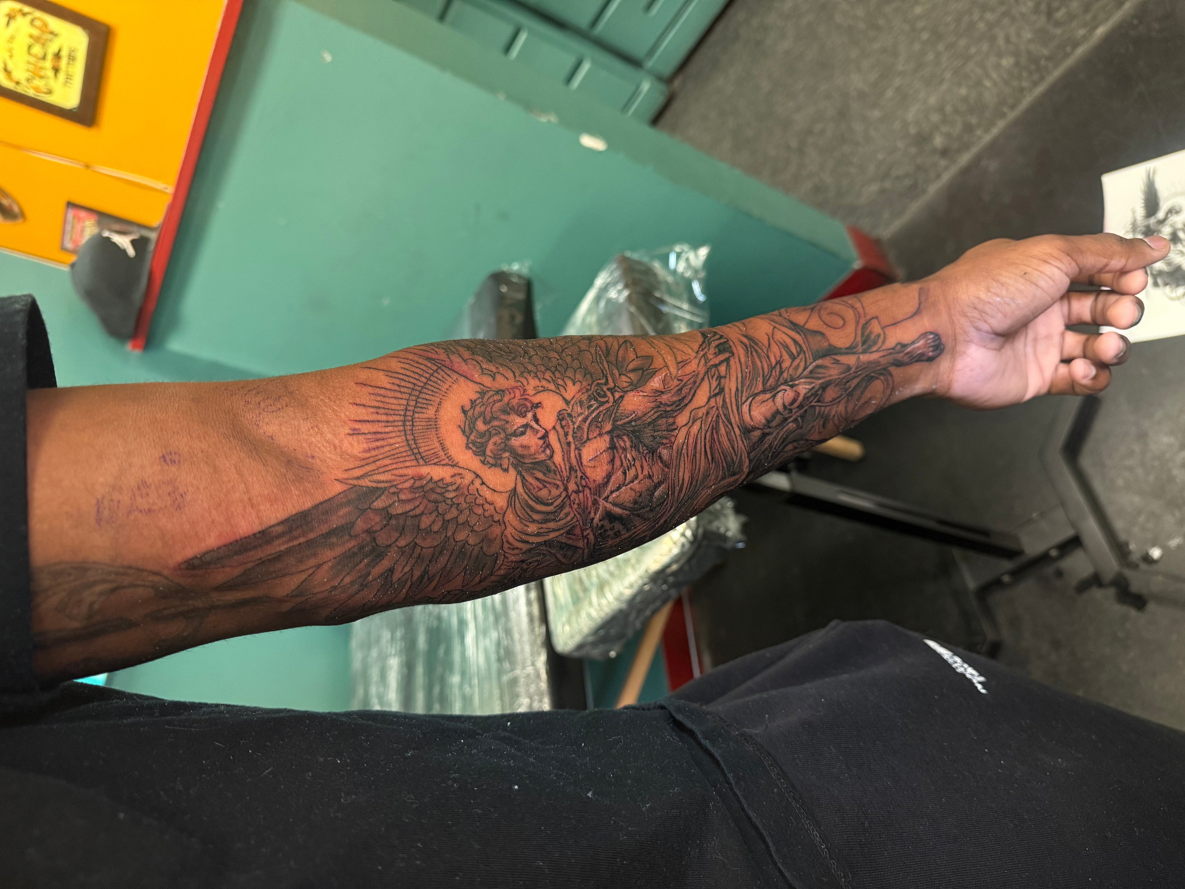 Person's arm with a detailed tattoo in a tattoo studio setting